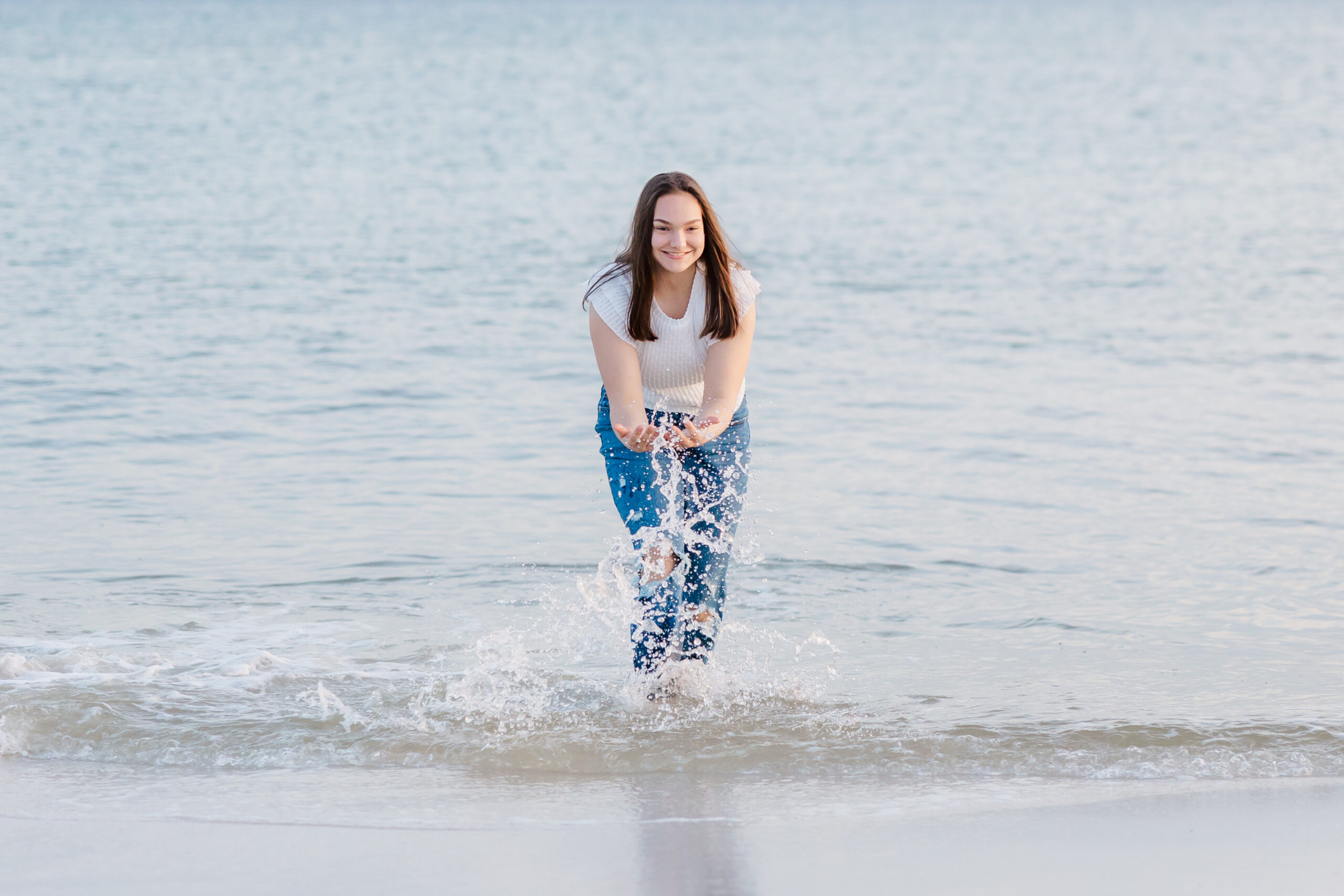 high school senior girl splashing in the ocean