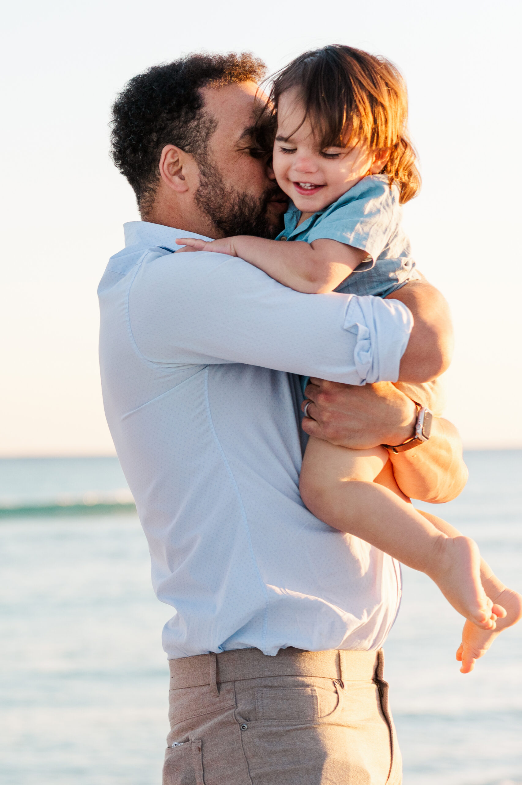Dad holding and kissing his son who is smiling